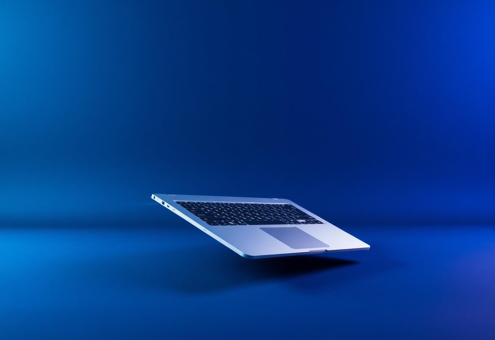 Swart ultrabook floating on a deep blue backdrop
